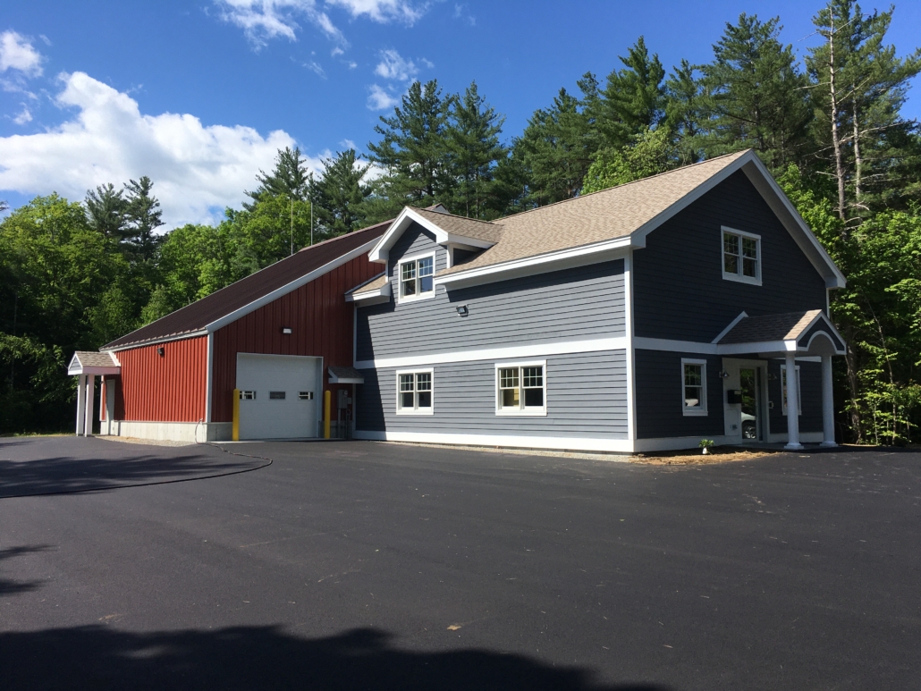 Lower Bartlett Water Precinct building is a two-story building with blue-grey horizontal siding and white trim attached to a larger red barn type section with a white garage door